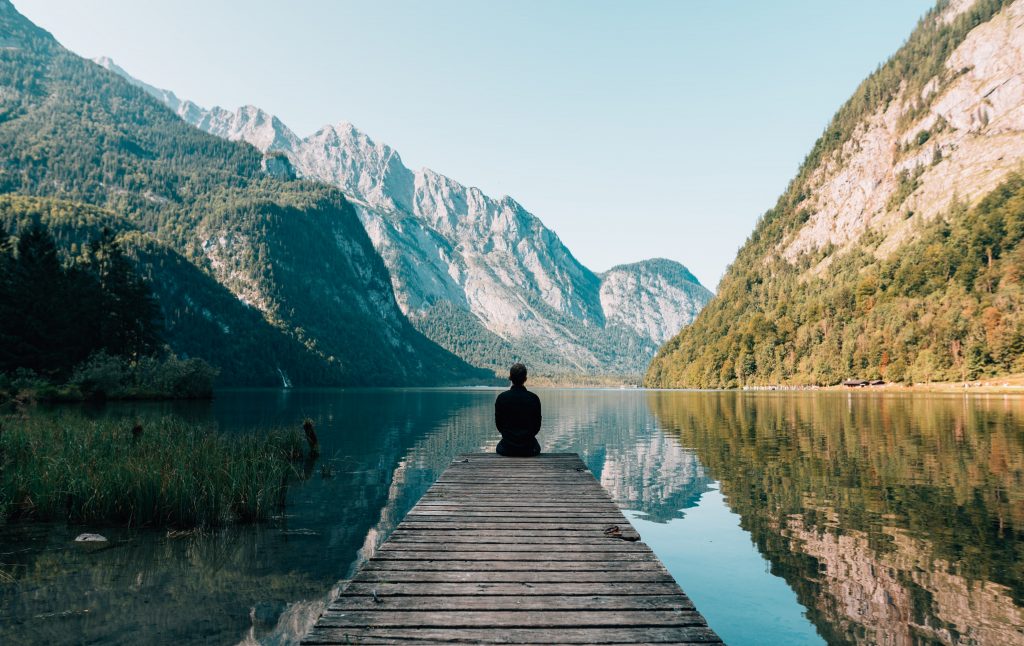 Person sitting on a dock looking at mountains