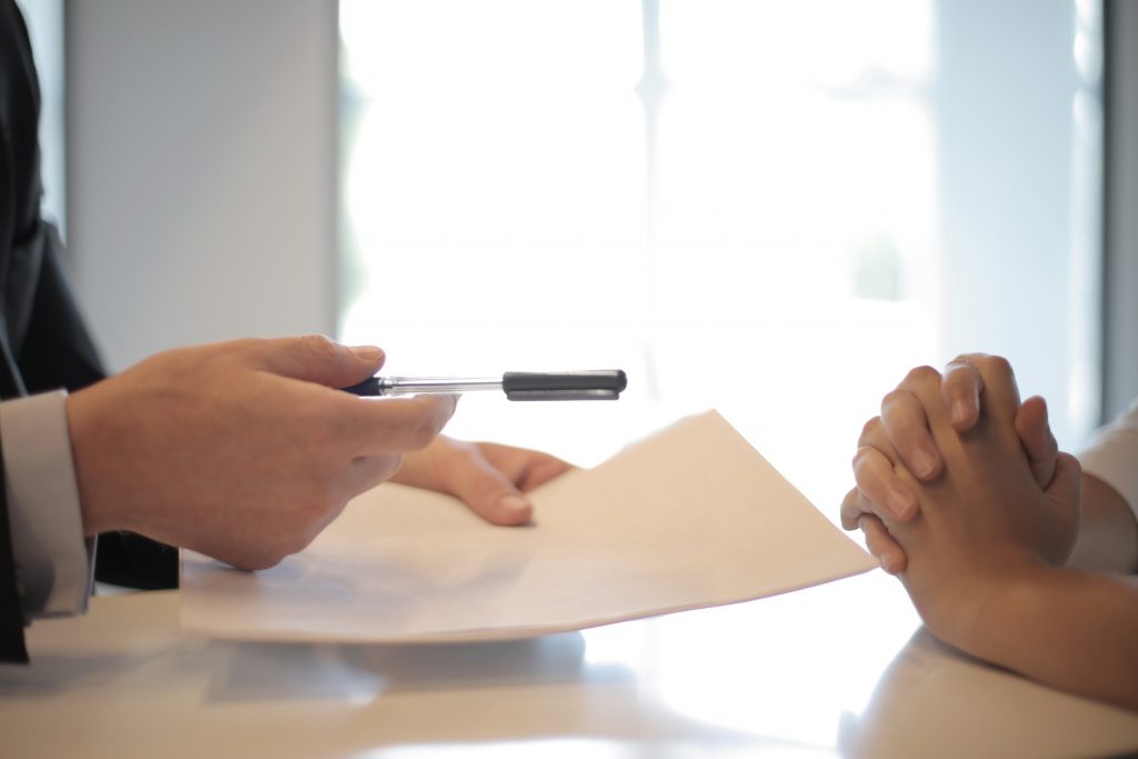 Two people handling a contract with a pen