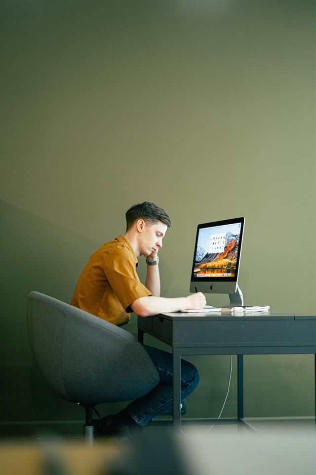 A man sitting on a chair and working on a laptop